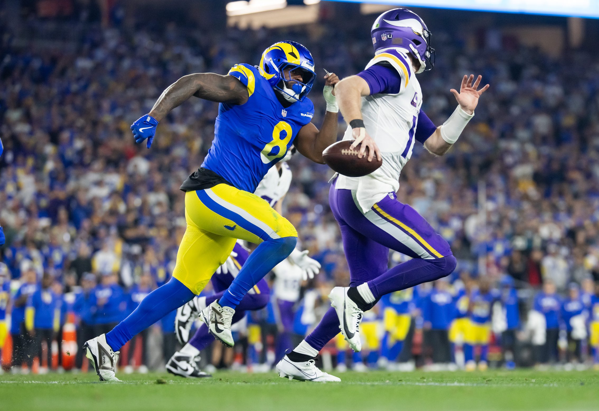 Jan 13, 2025; Glendale, AZ, USA; Minnesota Vikings quarterback Sam Darnold (14) is pursued by Los Angeles Rams linebacker Jared Verse (8) during an NFC wild card game at State Farm Stadium. Mandatory Credit: Mark J. Rebilas-Imagn Images