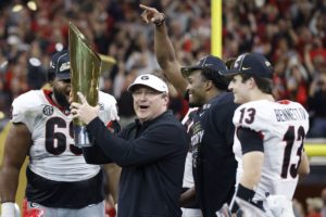Head Coach Kirby Smart hold up championship trophy as he celebrates with players
