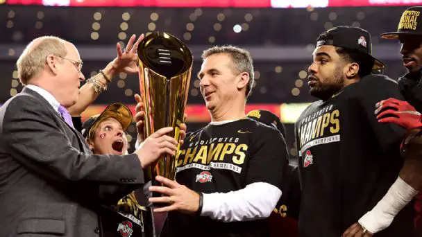 Urban Meyer being handled the 2014 CFP trophy 