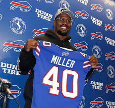 Von Miller holding up Bills jersey after being signed by them in free agency