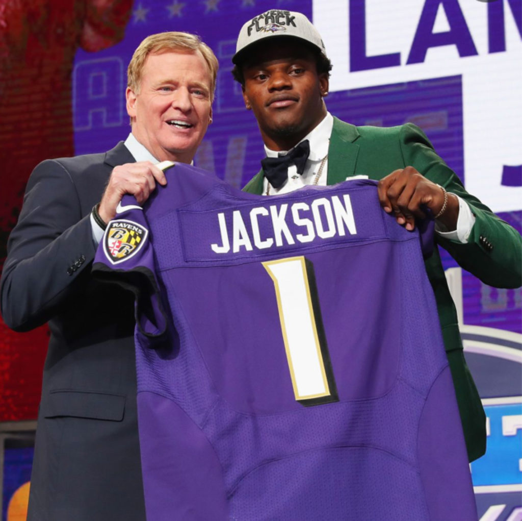 Lamar Jackson holding his draft night Ravens jersey.