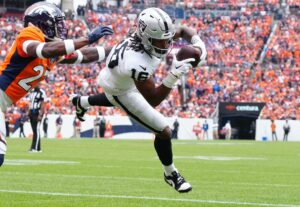 Sep 10, 2023; Denver, Colorado, USA; Las Vegas Raiders wide receiver Jakobi Meyers (16) catches a touchdown pass with Denver Broncos cornerback Damarri Mathis (27) defending in the first quarter at Empower Field at Mile High. Mandatory Credit: Ron Chenoy-USA TODAY Sports