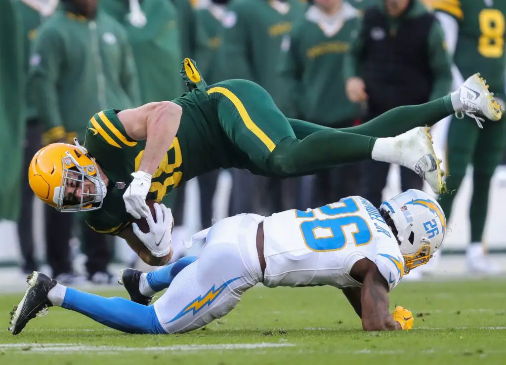 Green Bay Packers tight end Luke Musgrave (88) is upended by Los Angeles Chargers cornerback Asante Samuel Jr. (26) on Sunday, November 19, 2023, at Lambeau Field in Green Bay, Wis. The Packers won the game, 23-20.