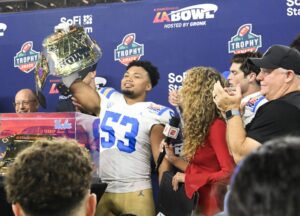 Dec 16, 2023; Inglewood, CA, USA; UCLA Bruins linebacker Darius Muasau (53) holds up the award for defensive player of the game after defeating the Boise State Broncos in the Starco Brands LA Bowl at SoFi Stadium. At right is UCLA head coach Chip Kelly. Mandatory Credit: Robert Hanashiro-USA TODAY Sports