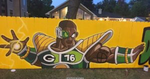 Artist Spencer Young makes a fence painting on Packer's DE Mike Daniels as a Saiyan.