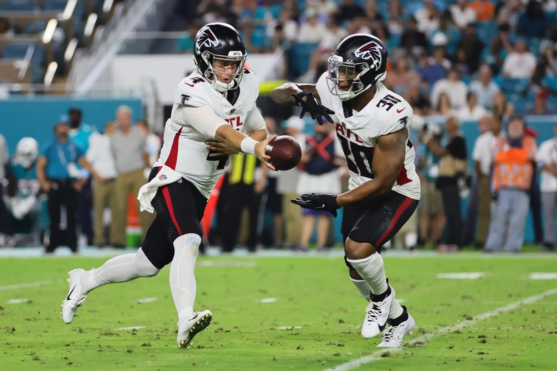 Aug 9, 2024; Miami Gardens, Florida, USA; Atlanta Falcons quarterback Taylor Heinicke (4) hands off the football to Atlanta Falcons running back Jase McClellan (30) against the Miami Dolphins during the third quarter at Hard Rock Stadium. Mandatory Credit: Sam Navarro-USA TODAY Sports