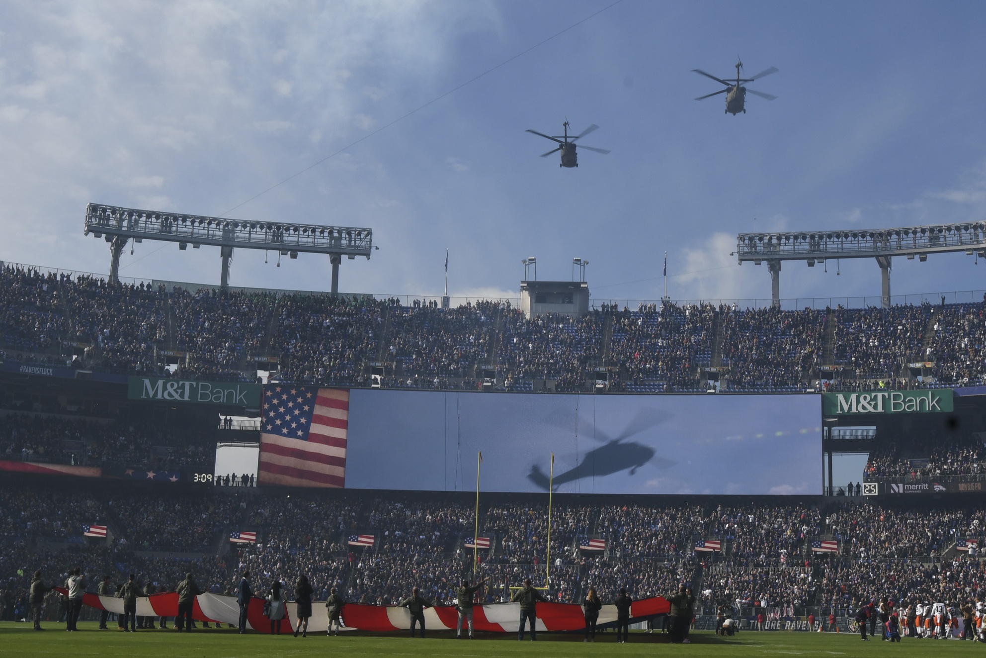 Nov 12, 2023; Baltimore, Maryland, USA; A military helicopter fly over is conducts as an American flag is unfurled during the playing of the national anthem before the start of the game between the Baltimore Ravens and the Cleveland Browns at M&T Bank Stadium. Mandatory Credit: Tommy Gilligan-Imagn Images