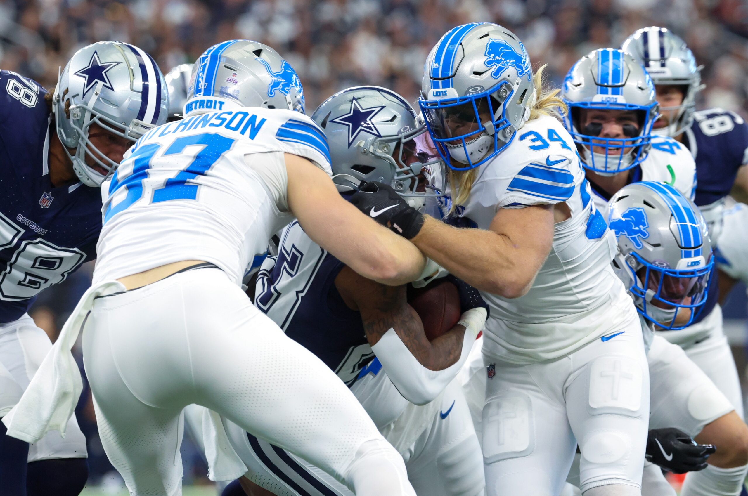 Oct 13, 2024; Arlington, Texas, USA; Dallas Cowboys running back Rico Dowdle (23) is tackled by Detroit Lions linebacker Alex Anzalone (34) and Detroit Lions defensive end Aidan Hutchinson (97) during the first quarter at AT&T Stadium. Mandatory Credit: Kevin Jairaj-Imagn Images