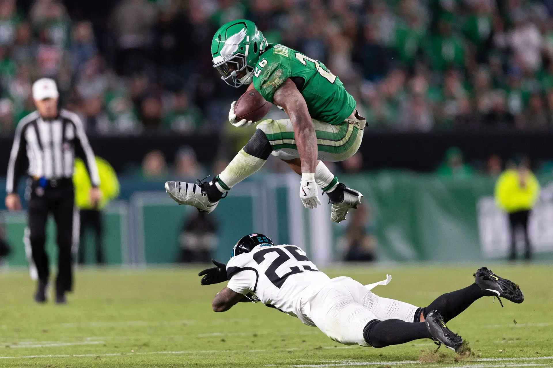 Nov 3, 2024; Philadelphia, Pennsylvania, USA; Philadelphia Eagles running back Saquon Barkley (26) leaps over Jacksonville Jaguars cornerback Ronald Darby (25) while running with the ball during the fourth quarter at Lincoln Financial Field. Mandatory Credit: Bill Streicher-Imagn Images