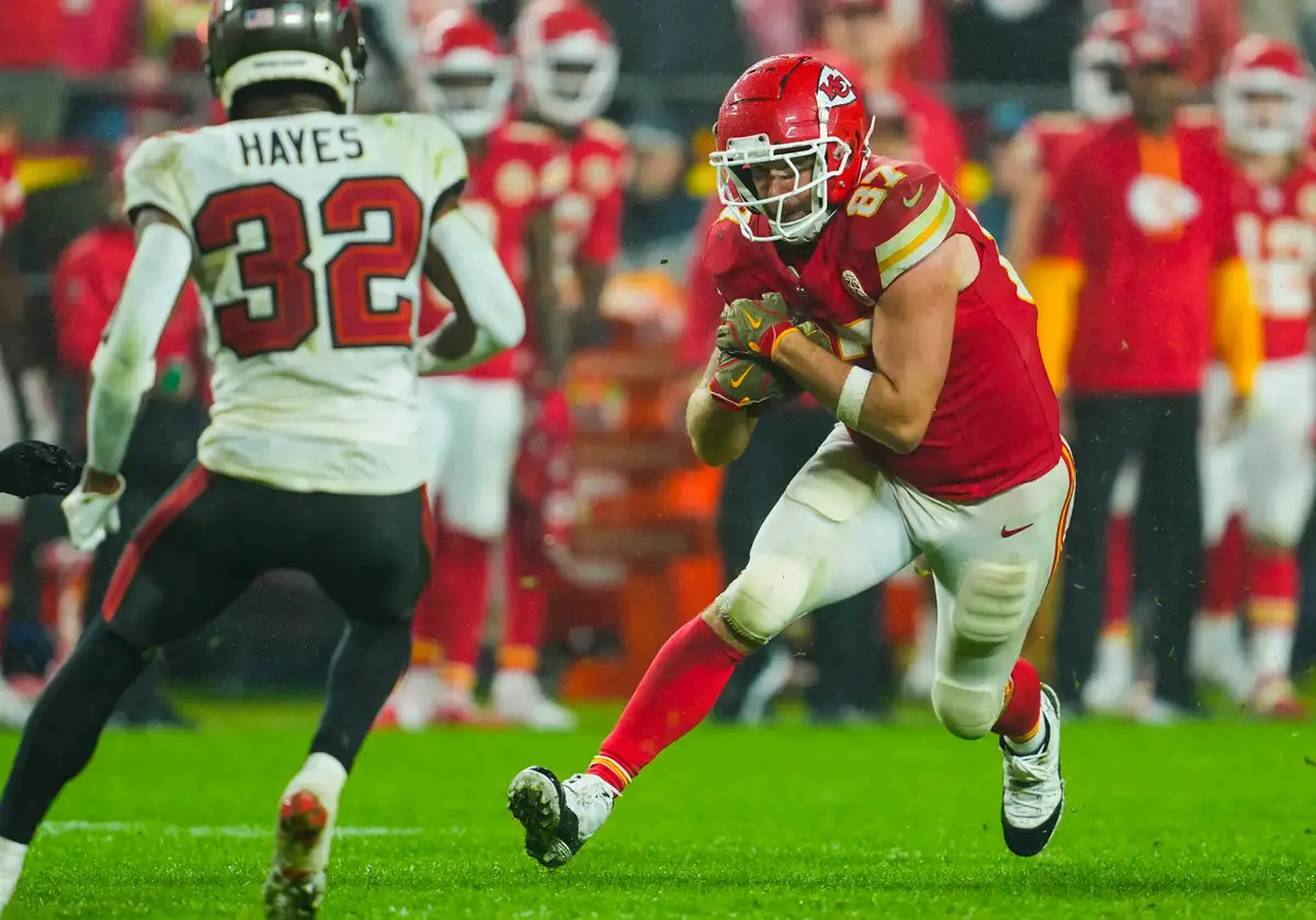 Nov 4, 2024; Kansas City, Missouri, USA; Kansas City Chiefs tight end Travis Kelce (87) runs with the ball against Tampa Bay Buccaneers safety Josh Hayes (32) during overtime at GEHA Field at Arrowhead Stadium. Mandatory Credit: Jay Biggerstaff-Imagn Images