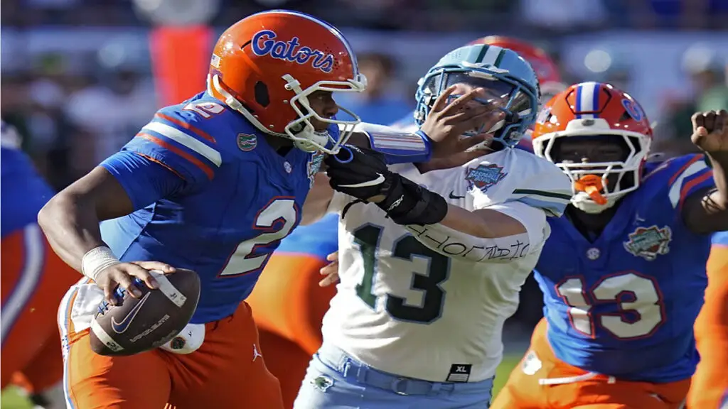 Florida quarterback DJ Lagway stiff arms Tulane linebacker Tyler Grubbs during the first half of the Gasparilla Bowl (AP Photo).