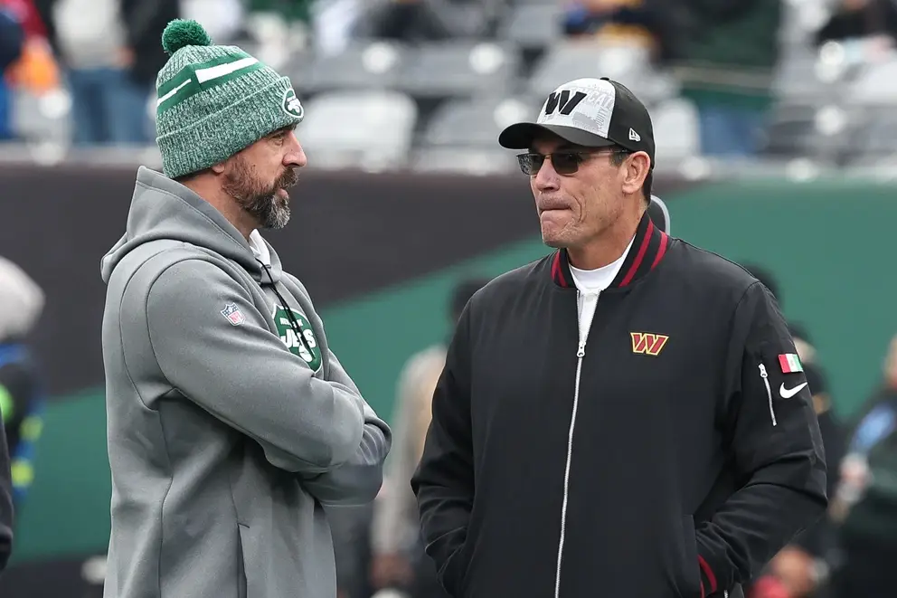 Dec 24, 2023; East Rutherford, New Jersey, USA; New York Jets quarterback Aaron Rodgers (left) talks with Washington Commanders head coach Ron Rivera before the game at MetLife Stadium. Mandatory Credit: Vincent Carchietta-Imagn Images