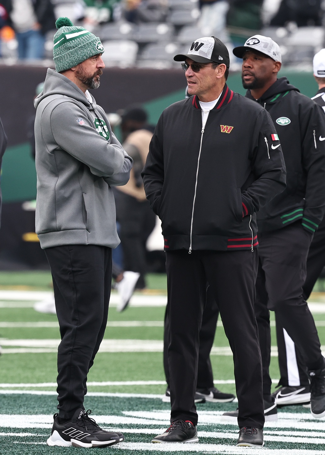 Dec 24, 2023; East Rutherford, New Jersey, USA; New York Jets quarterback Aaron Rodgers (left) talks with Washington Commanders head coach Ron Rivera before the game at MetLife Stadium. Mandatory Credit: Vincent Carchietta-Imagn Images