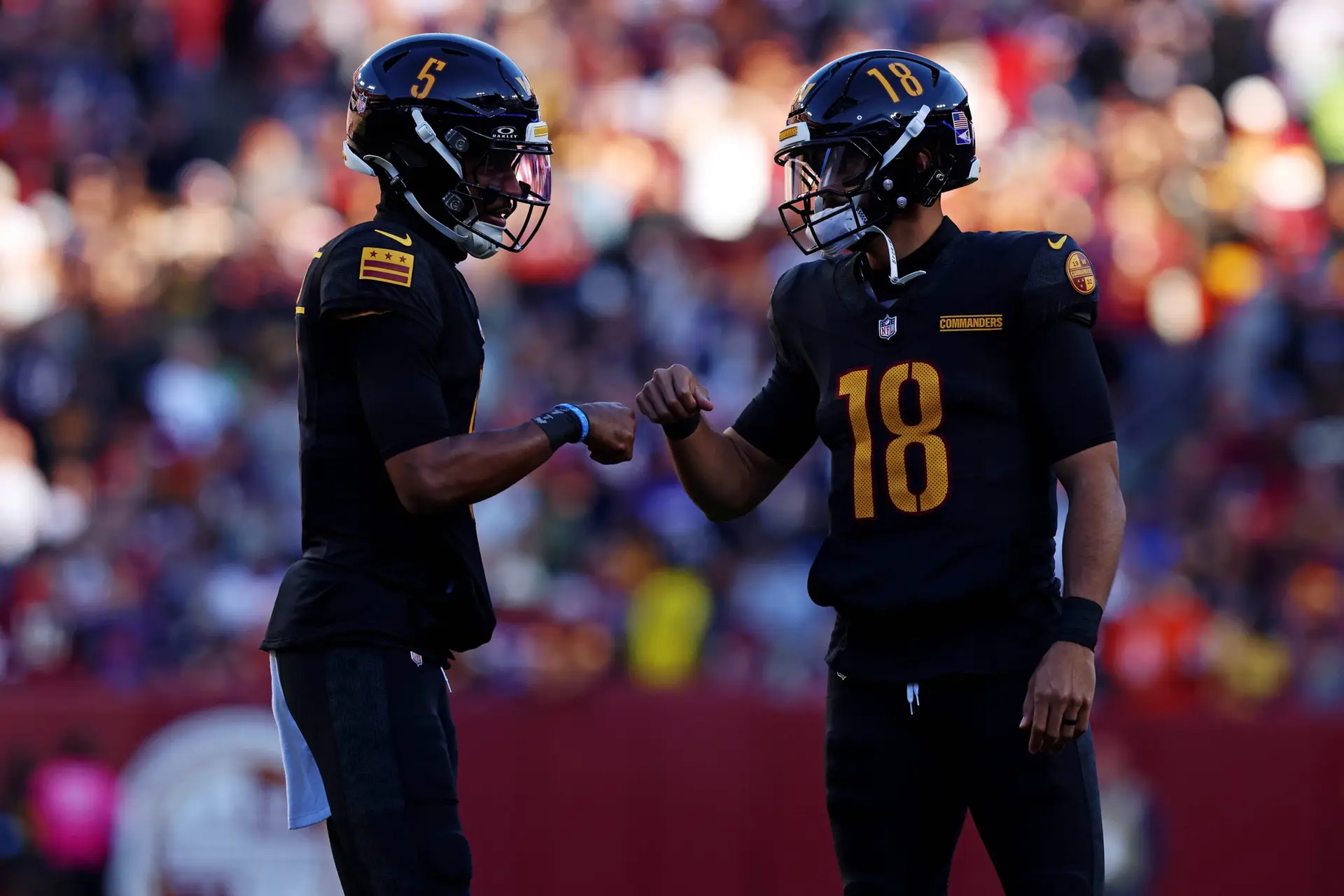 Oct 27, 2024; Landover, Maryland, USA; Washington Commanders quarterback Jayden Daniels (5) and quarterback Marcus Mariota (18) talk to each other during the first half against the Chicago Bears at Commanders Field. Mandatory Credit: Peter Casey-Imagn Images