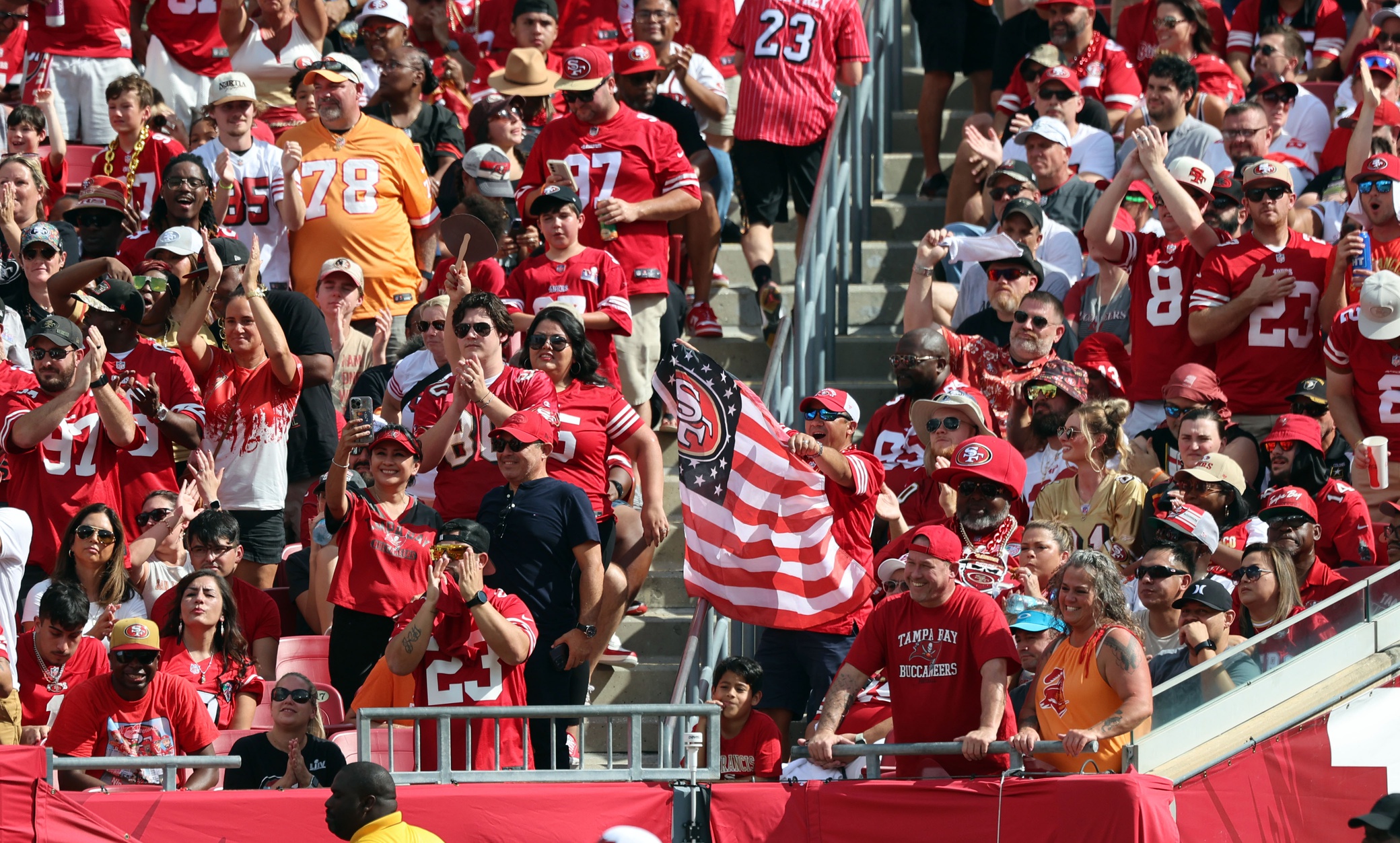 Nov 10, 2024; Tampa, Florida, USA; San Francisco 49ers fans cheer and hold up an American flag against the Tampa Bay Buccaneers during the first half at Raymond James Stadium. Mandatory Credit: Kim Klement Neitzel-Imagn Images