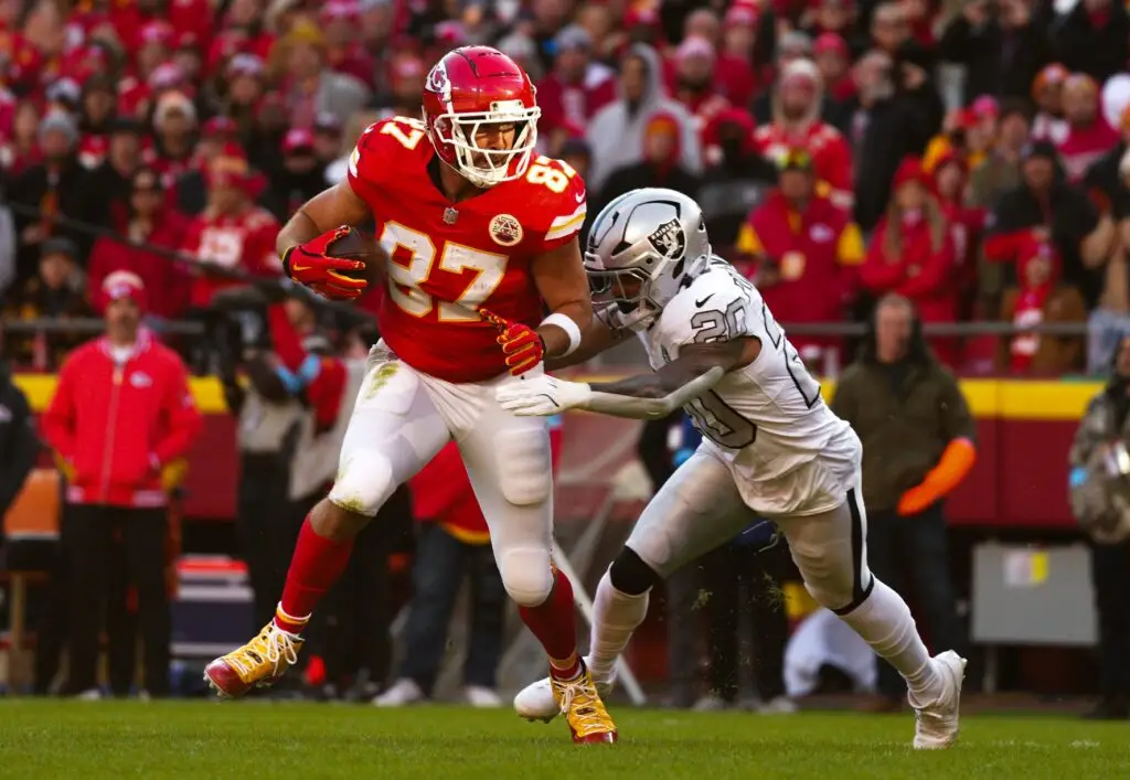 Nov 29, 2024; Kansas City, Missouri, USA; Kansas City Chiefs tight end Travis Kelce (87) runs with the ball against Las Vegas Raiders safety Isaiah Pola-Mao (20) during the first half at GEHA Field at Arrowhead Stadium. Mandatory Credit: Jay Biggerstaff-Imagn Images