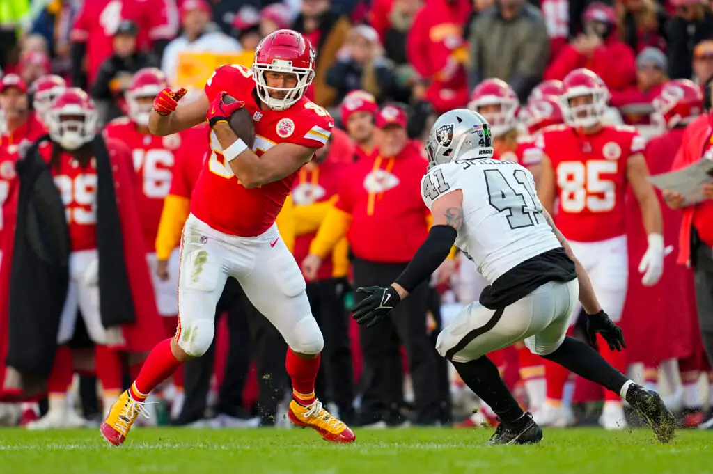 Nov 29, 2024; Kansas City, Missouri, USA; Kansas City Chiefs tight end Travis Kelce (87) runs with the ball against Las Vegas Raiders linebacker Robert Spillane (41) during the first half at GEHA Field at Arrowhead Stadium. Mandatory Credit: Jay Biggerstaff-Imagn Images