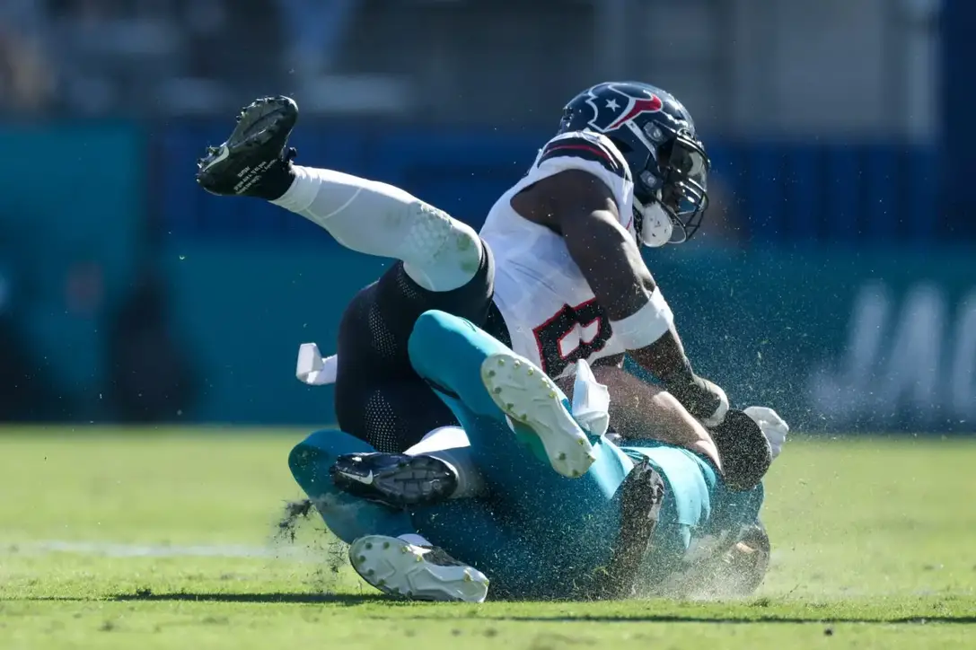 Dec 1, 2024; Jacksonville, Florida, USA; Jacksonville Jaguars quarterback Trevor Lawrence (16) is hit by Houston Texans linebacker Azeez Al-Shaair (0) as he slides down in the second quarter in the second quarter at EverBank Stadium. Mandatory Credit: Nathan Ray Seebeck-Imagn Images