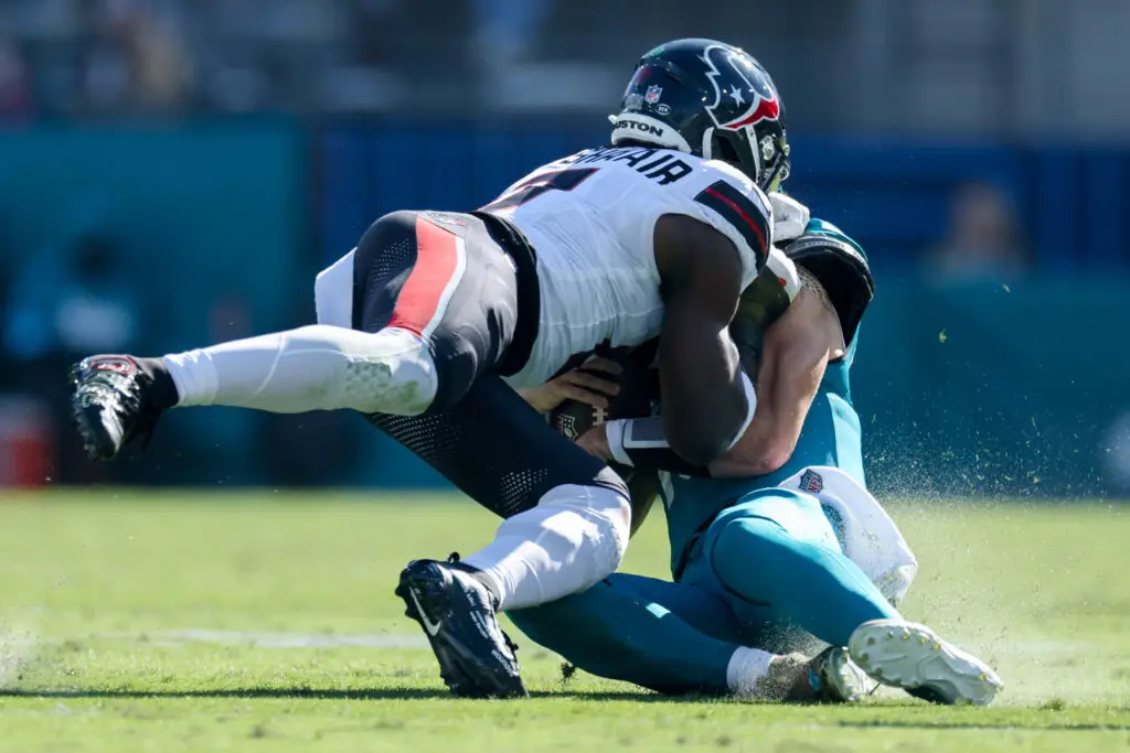 Dec 1, 2024; Jacksonville, Florida, USA; Jacksonville Jaguars quarterback Trevor Lawrence (16) is hit by Houston Texans linebacker Azeez Al-Shaair (0) as he slides down in the second quarter in the second quarter at EverBank Stadium. Mandatory Credit: Nathan Ray Seebeck-Imagn Images