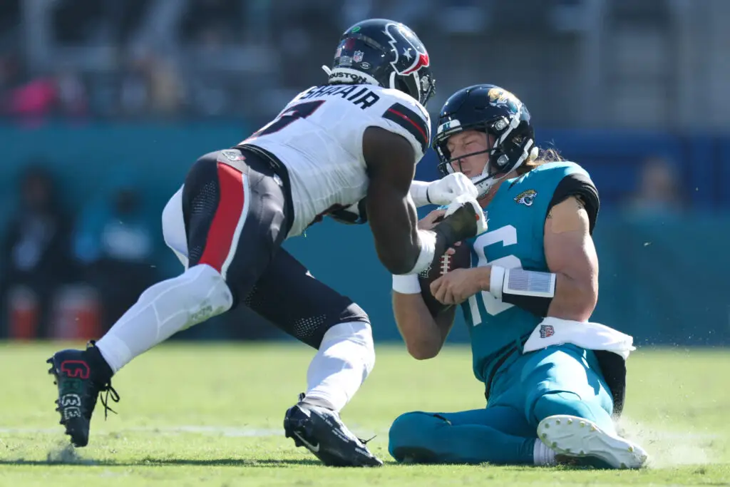 Dec 1, 2024; Jacksonville, Florida, USA; Jacksonville Jaguars quarterback Trevor Lawrence (16) slides down in front of Houston Texans linebacker Azeez Al-Shaair (0) in the second quarter in the second quarter at EverBank Stadium. Mandatory Credit: Nathan Ray Seebeck-Imagn Images