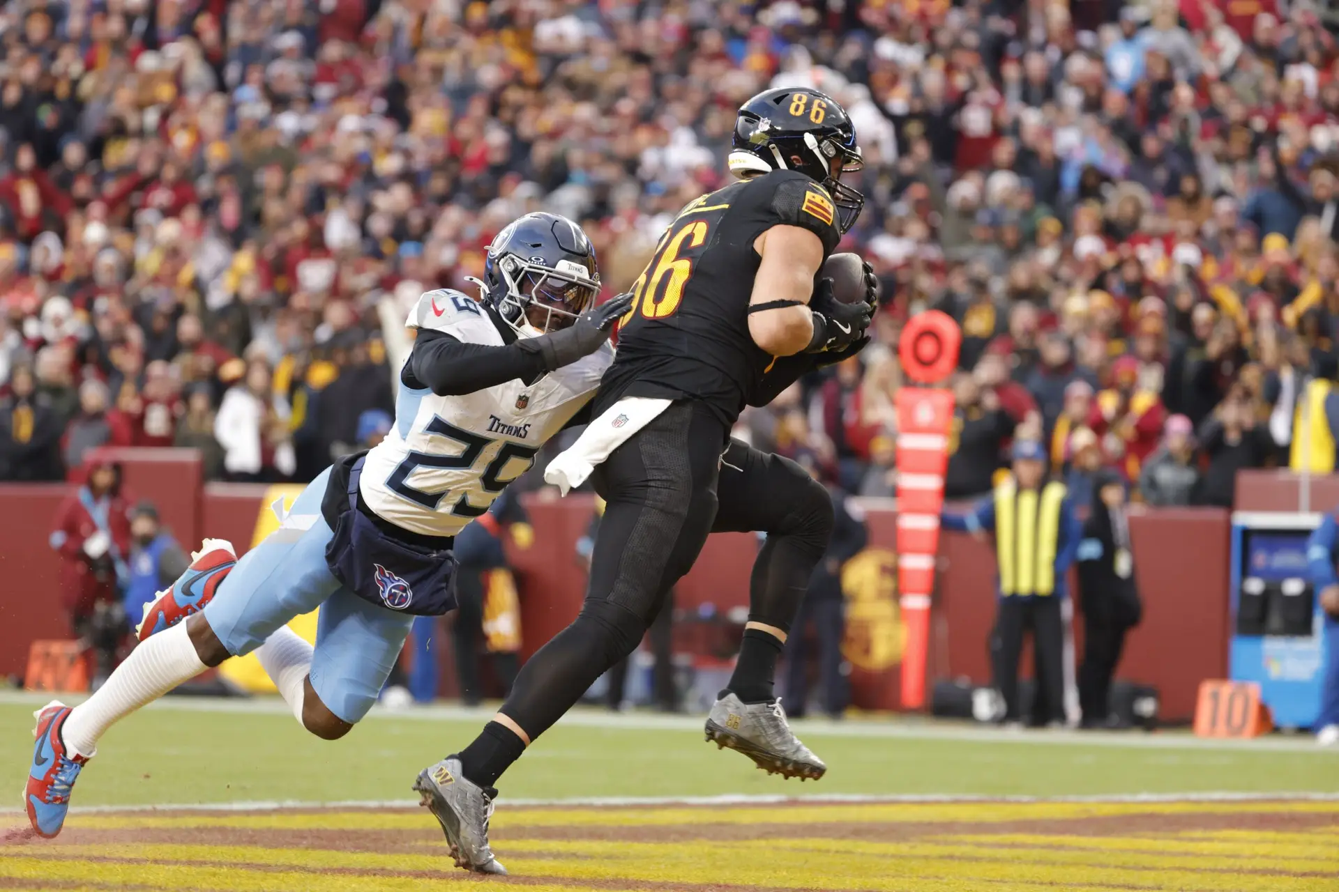 Dec 1, 2024; Landover, Maryland, USA; Washington Commanders tight end Zach Ertz (86) scores a touchdown past Tennessee Titans cornerback Jarvis Brownlee Jr. (29) during the second half at Northwest Stadium. Mandatory Credit: Amber Searls-Imagn Images