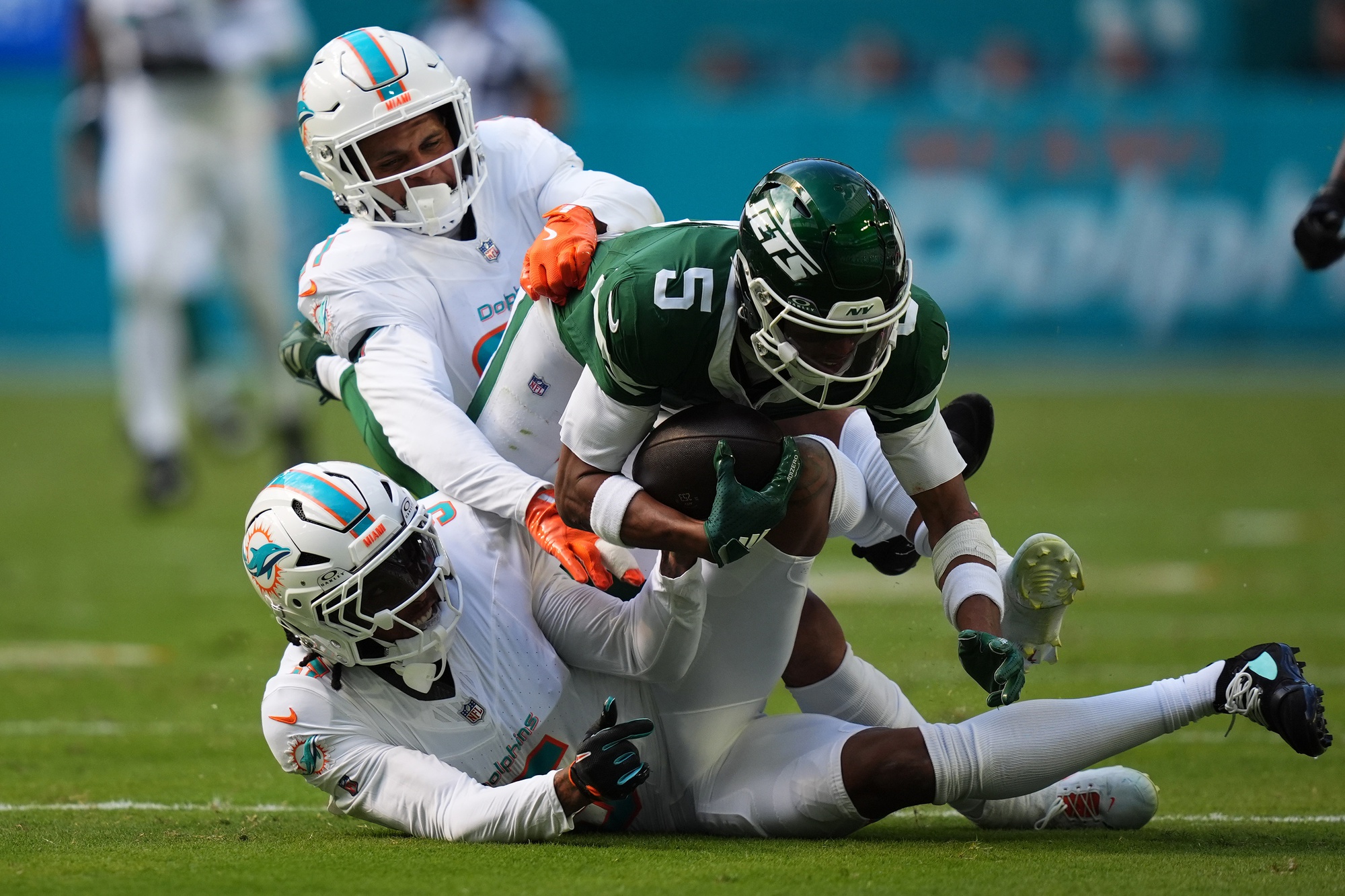 Dec 8, 2024; Miami Gardens, Florida, USA; Miami Dolphins cornerback Jalen Ramsey (5) and safety Jordan Poyer (21) tackle New York Jets wide receiver Garrett Wilson (5) during the first half at Hard Rock Stadium. Mandatory Credit: Jasen Vinlove-Imagn Images