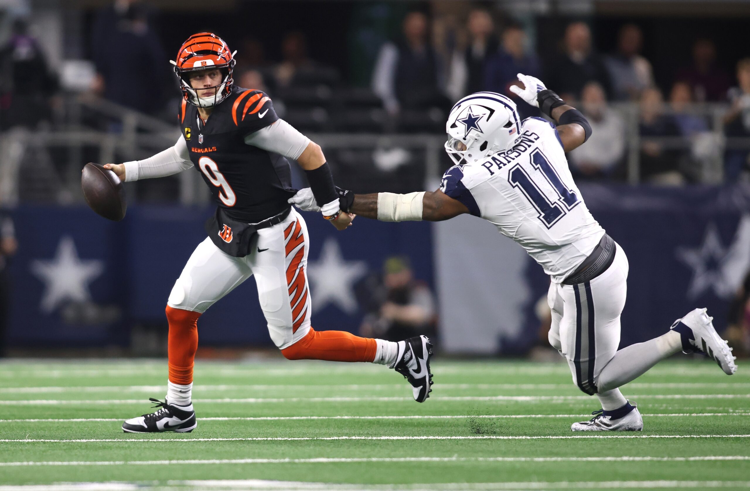 Dec 9, 2024; Arlington, Texas, USA; Cincinnati Bengals quarterback Joe Burrow (9) avoids the tackle of Dallas Cowboys linebacker Micah Parsons (11) in the second half at AT&T Stadium. Mandatory Credit: Tim Heitman-Imagn Images