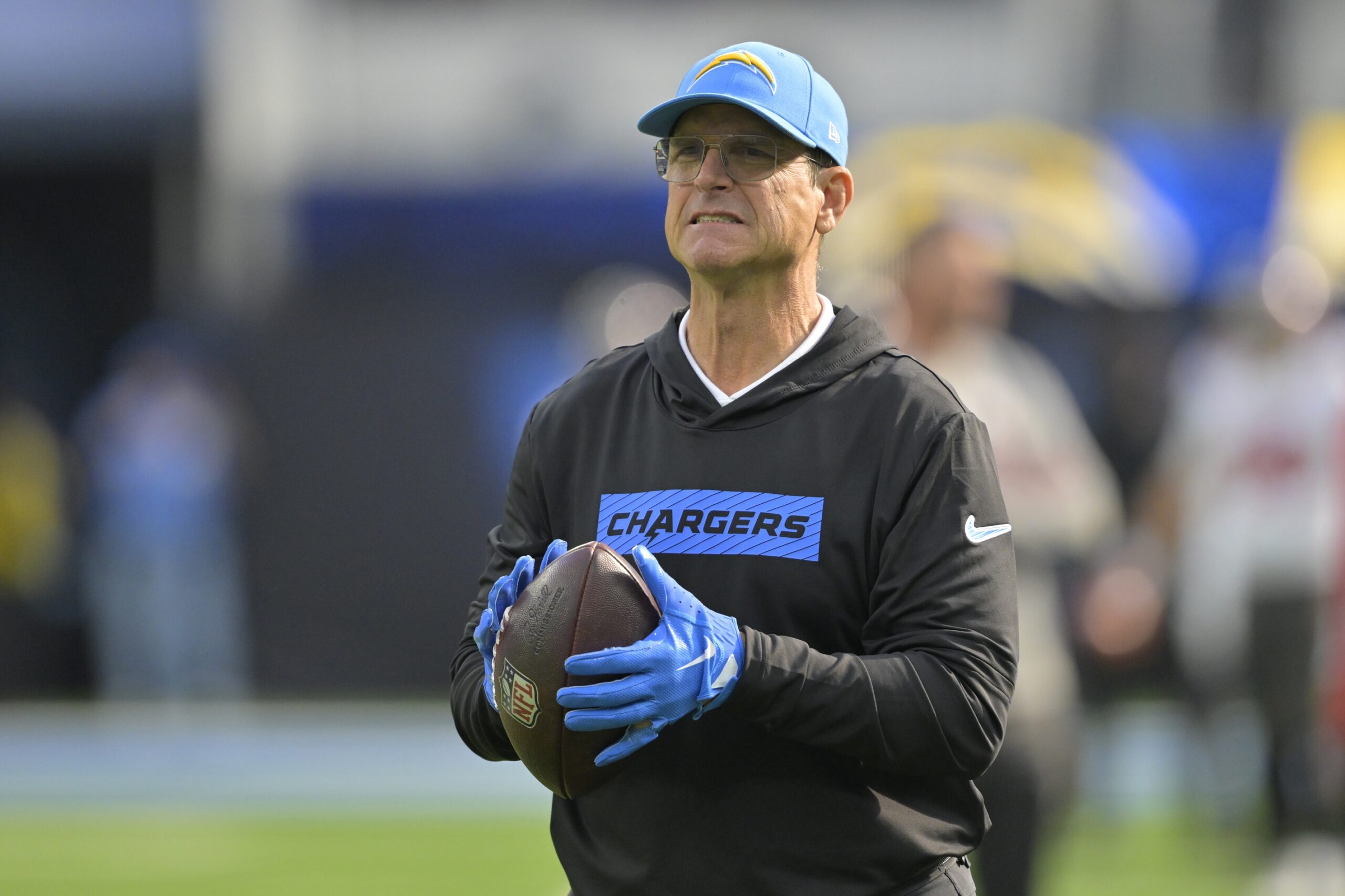 Dec 15, 2024; Inglewood, California, USA; Los Angeles Chargers head coach Jim Harbaugh tosses a football on the field prior to the game against the Tampa Bay Buccaneers at SoFi Stadium. Mandatory Credit: Jayne Kamin-Oncea-Imagn Images