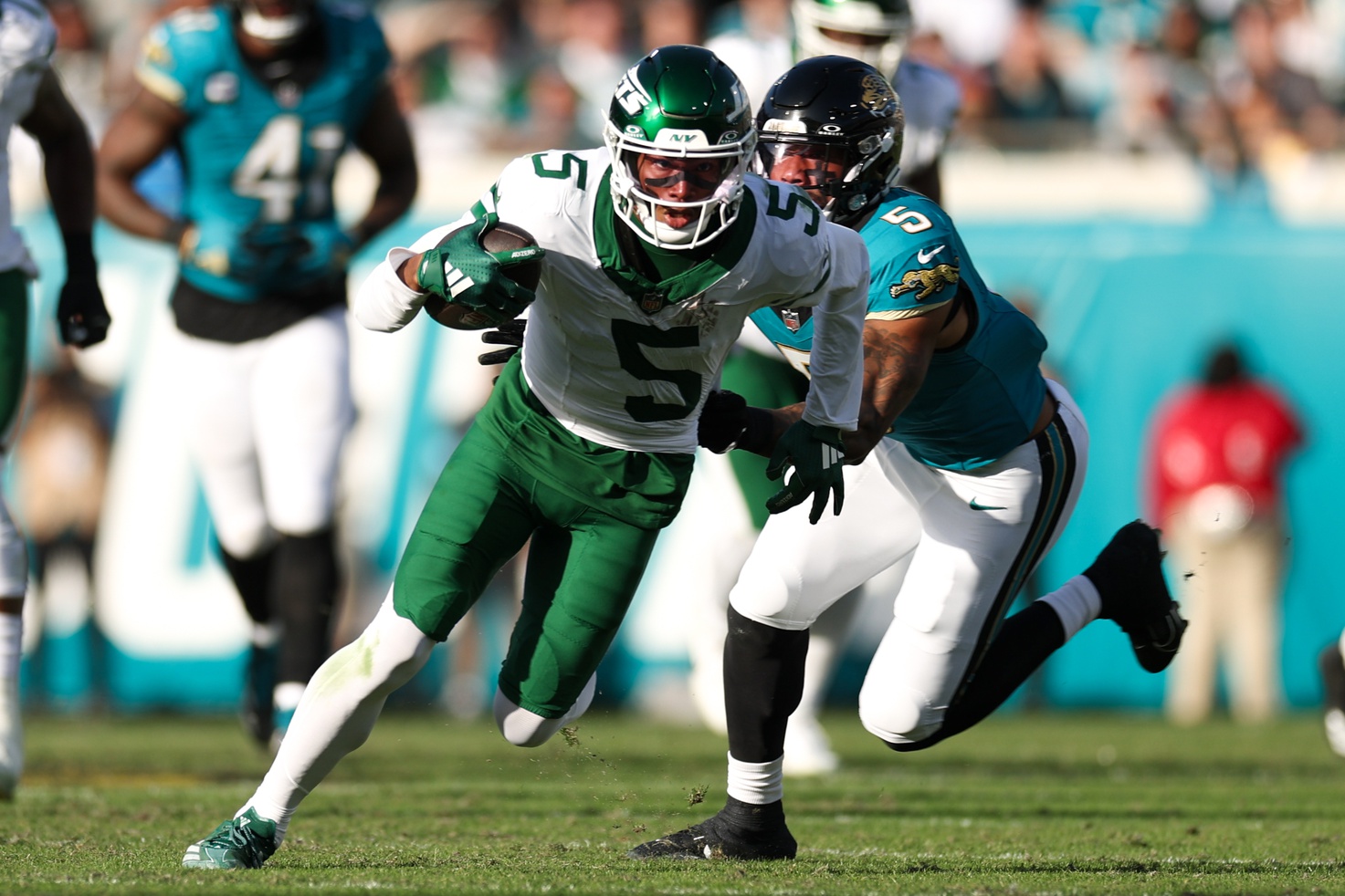 Dec 15, 2024; Jacksonville, Florida, USA; New York Jets wide receiver Garrett Wilson (5) runs with the ball chased by Jacksonville Jaguars safety Andre Cisco (5) in the fourth quarter at EverBank Stadium. Mandatory Credit: Nathan Ray Seebeck-Imagn Images