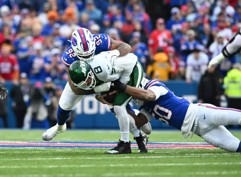 Dec 29, 2024; Orchard Park, New York, USA; New York Jets quarterback Aaron Rodgers (8) is sacked by Buffalo Bills defensive tackle DaQuan Jones (92) and defensive end Greg Rousseau (50) in the third quarter at Highmark Stadium. Mandatory Credit: Mark Konezny-Imagn Images