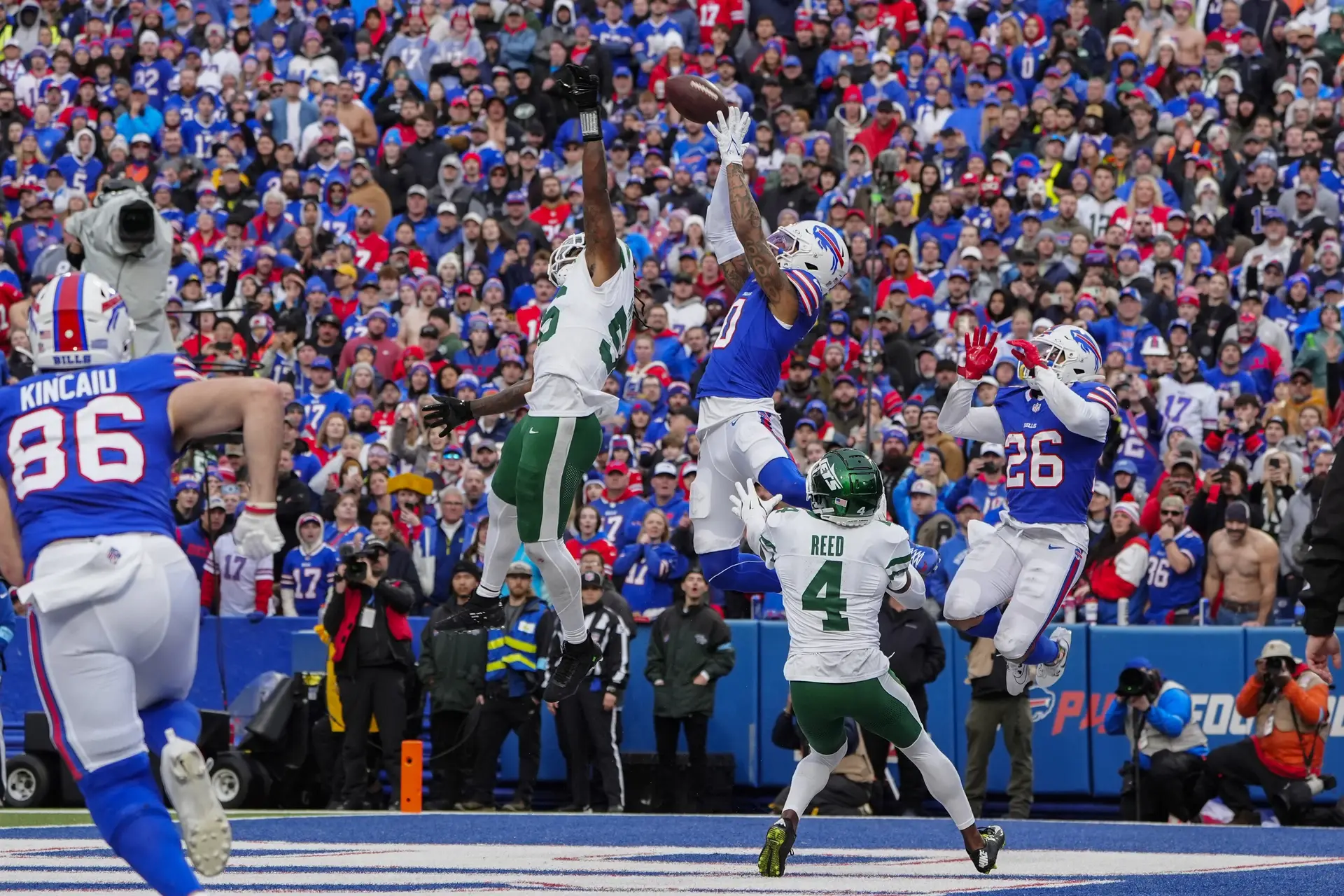 Dec 29, 2024; Orchard Park, New York, USA; Buffalo Bills wide receiver Keon Coleman (0) makes a catch for a touchdown against New York Jets linebacker Chazz Surratt (55) and New York Jets cornerback D.J. Reed (4) during the second half at Highmark Stadium. Mandatory Credit: Gregory Fisher-Imagn Images