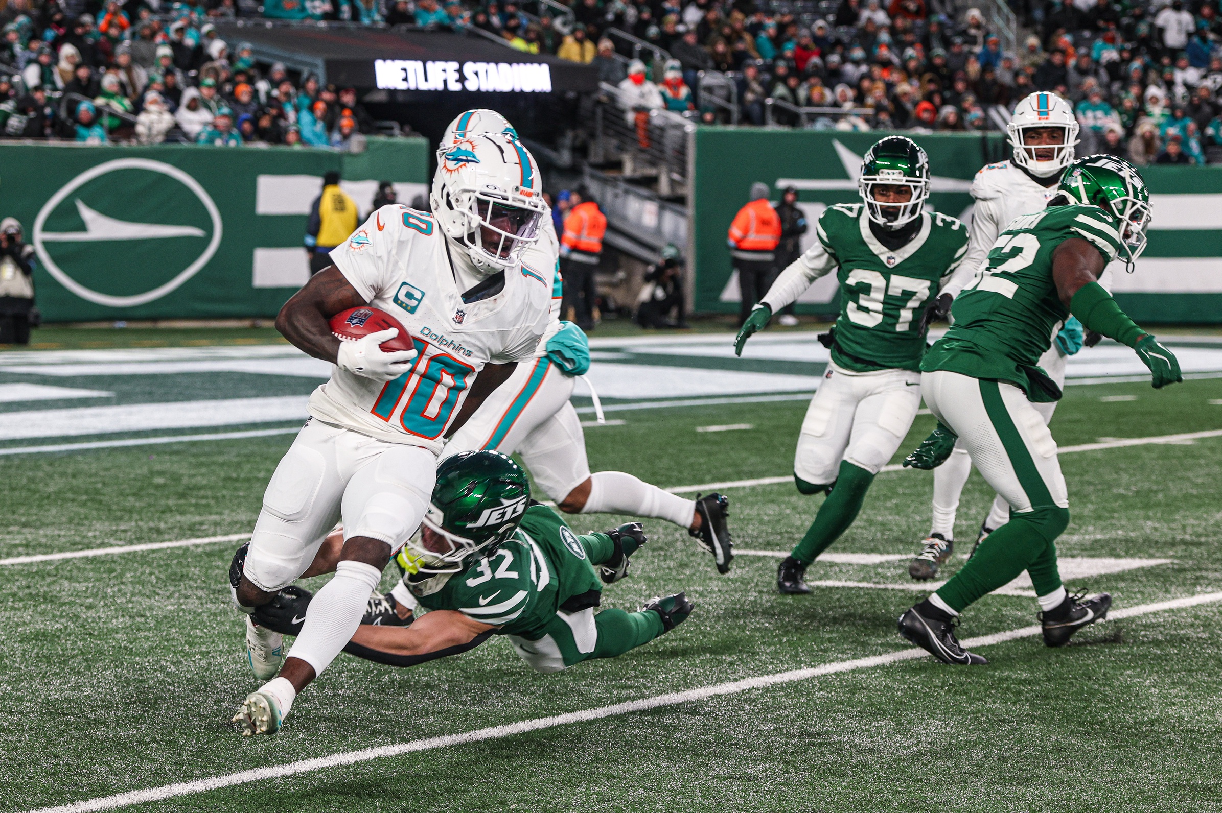 Jan 5, 2025; East Rutherford, New Jersey, USA; Miami Dolphins wide receiver Tyreek Hill (10) is tackled by New York Jets running back Isaiah Davis (32) during a punt return during the first half at MetLife Stadium. Mandatory Credit: Vincent Carchietta-Imagn Images